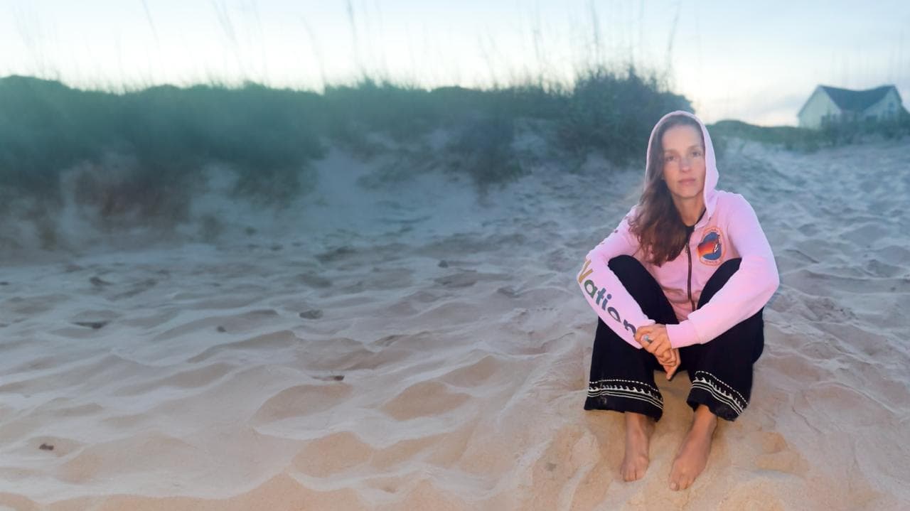 Stephanie sitting on beach in hoodie